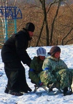 Фото. Владивосток. Духовный наставник Димитриевских игр, руководитель центра «Объятия Отча» иерей Даниил Нефедьев помогает юным участникам соревнований преодолеть эстафету на санках